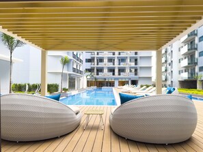 Un espace piscine avec des chaises longues et une terrasse couverte.