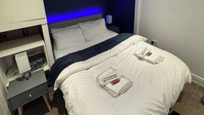 A modern hotel room with a bed, built-in storage, a skylight, and a nightstand. - Tranquil Cambridge Getaway (Cambridge)