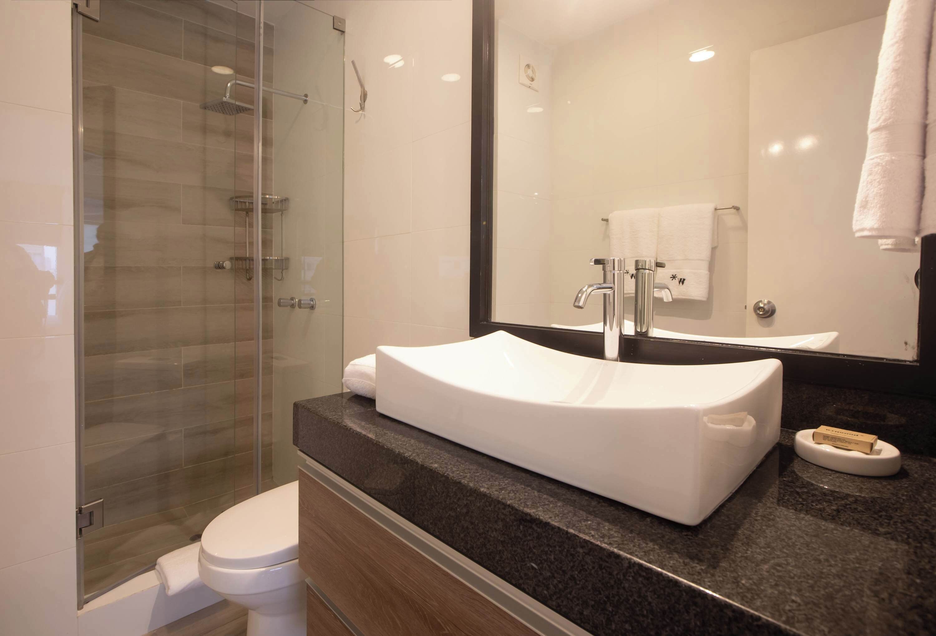 A modern bathroom with a glass-enclosed shower, a white sink, and a large mirror.