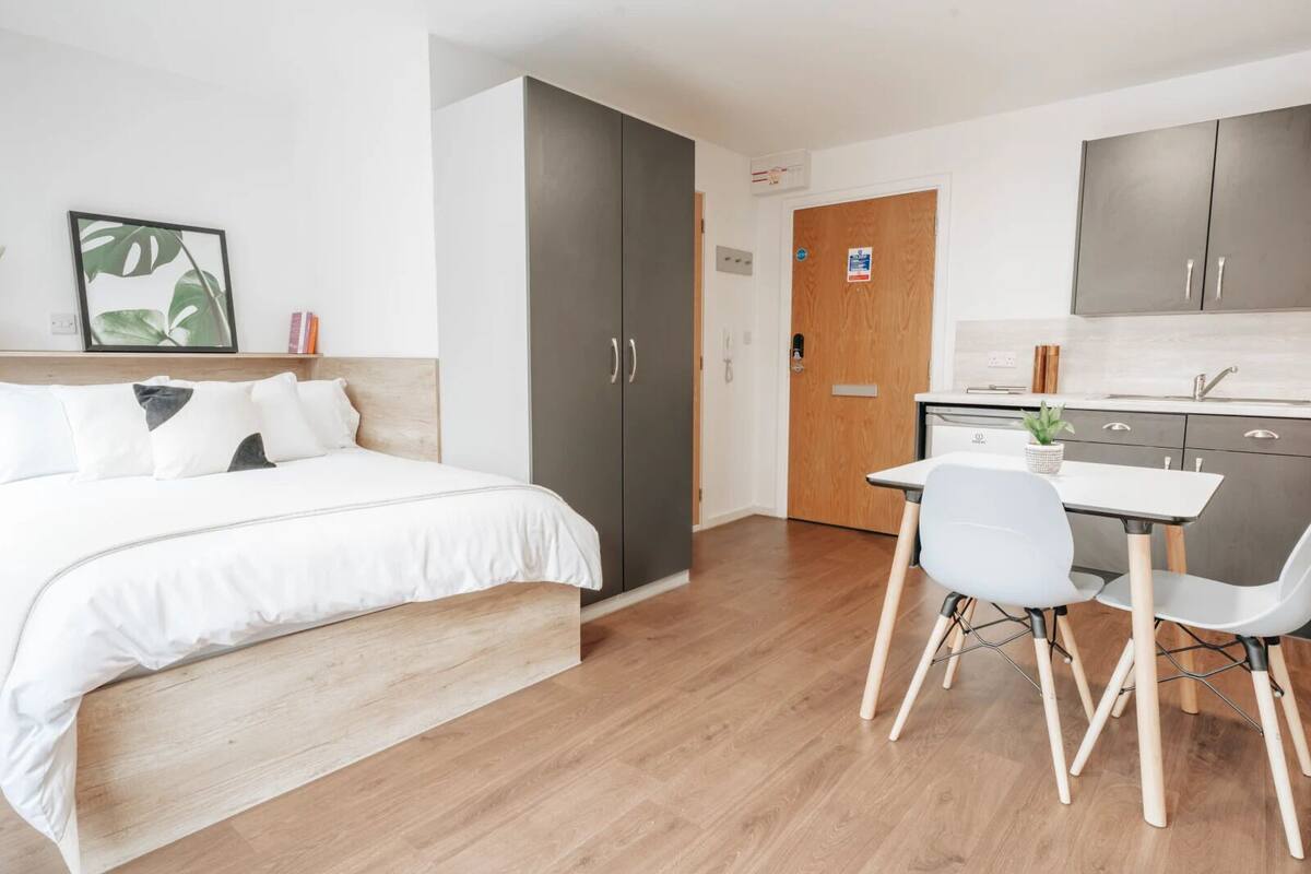 Ein modernes Hotelzimmer mit Bett, Schreibtisch und einer Küchenzeile.
