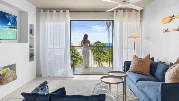 A modern living room with a balcony, a ceiling fan, and a view of the sea. - Oceanic Views at Kings Beach - 300m to the beach (Caloundra Region)