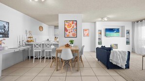 A modern living space with a dining area, a sofa, and a TV. - Oceanic Views at Kings Beach - 300m to the beach (Caloundra Region)