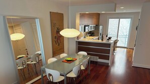 A modern kitchen with a built-in island, white cabinets, and stainless steel appliances.