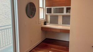 A small kitchen with wooden cabinets, a window, and a round mirror.