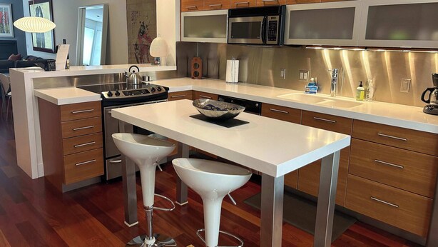 A modern kitchen with stainless steel appliances, wooden cabinets, and a central island with bar stools.