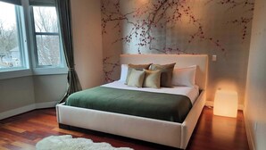 A bedroom with a large bed, a fluffy rug, and a wall mural.
