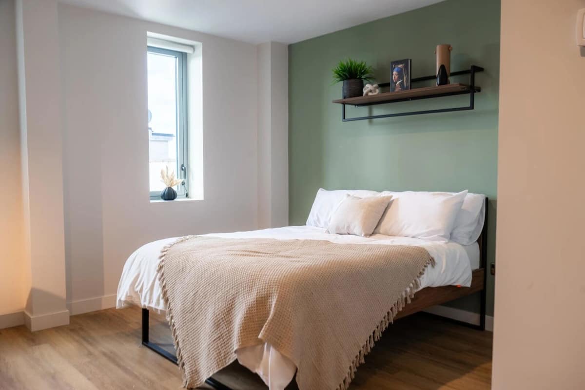 A bedroom with a bed, a window, and a shelf with decorative items.