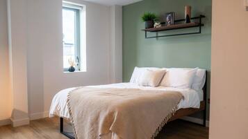 A bedroom with a bed, a window, and a shelf with decorative items.