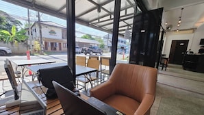 Ein modernes Café mit einem Laptop auf einem Tisch, einem braunen Ledersessel und Blick auf die Straße.