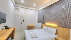 Ein Hotelzimmer mit einem Bett, einem Holztisch, einem Fernseher und einer Wand mit Muster.