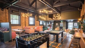 Un grand espace intérieur comprenant une table de baby-foot, des canapés et une table de billard.