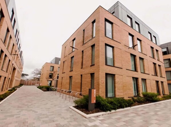 A modern building with a brick facade, multiple windows, and a paved walkway. - For Students Only Hox Park (Englefield Green)