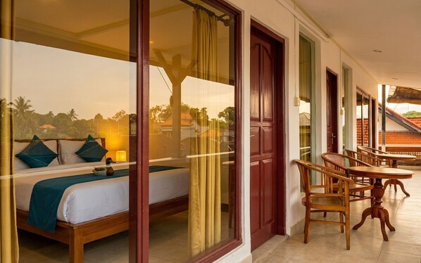 A hotel room with a bed, a table, and chairs, and a view of the outside. - Rumah Rini by Rumah Weda (Ubud)