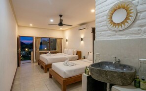 A hotel room with two beds, a large stone sink, a ceiling fan, and a view of the outdoors. - Rumah Rini by Rumah Weda (Ubud)
