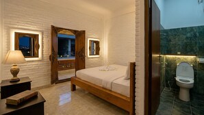 Une chambre à coucher avec un lit en bois, une table de chevet avec une lampe, un miroir et une vue sur l’extérieur.