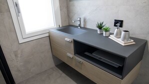 A modern bathroom with a grey sink, wooden cabinet, and potted plants. - VivimiHome - Monti House (Monti)