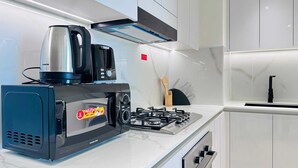 Una cocina moderna con microondas, estufa y cafetera integrados.
