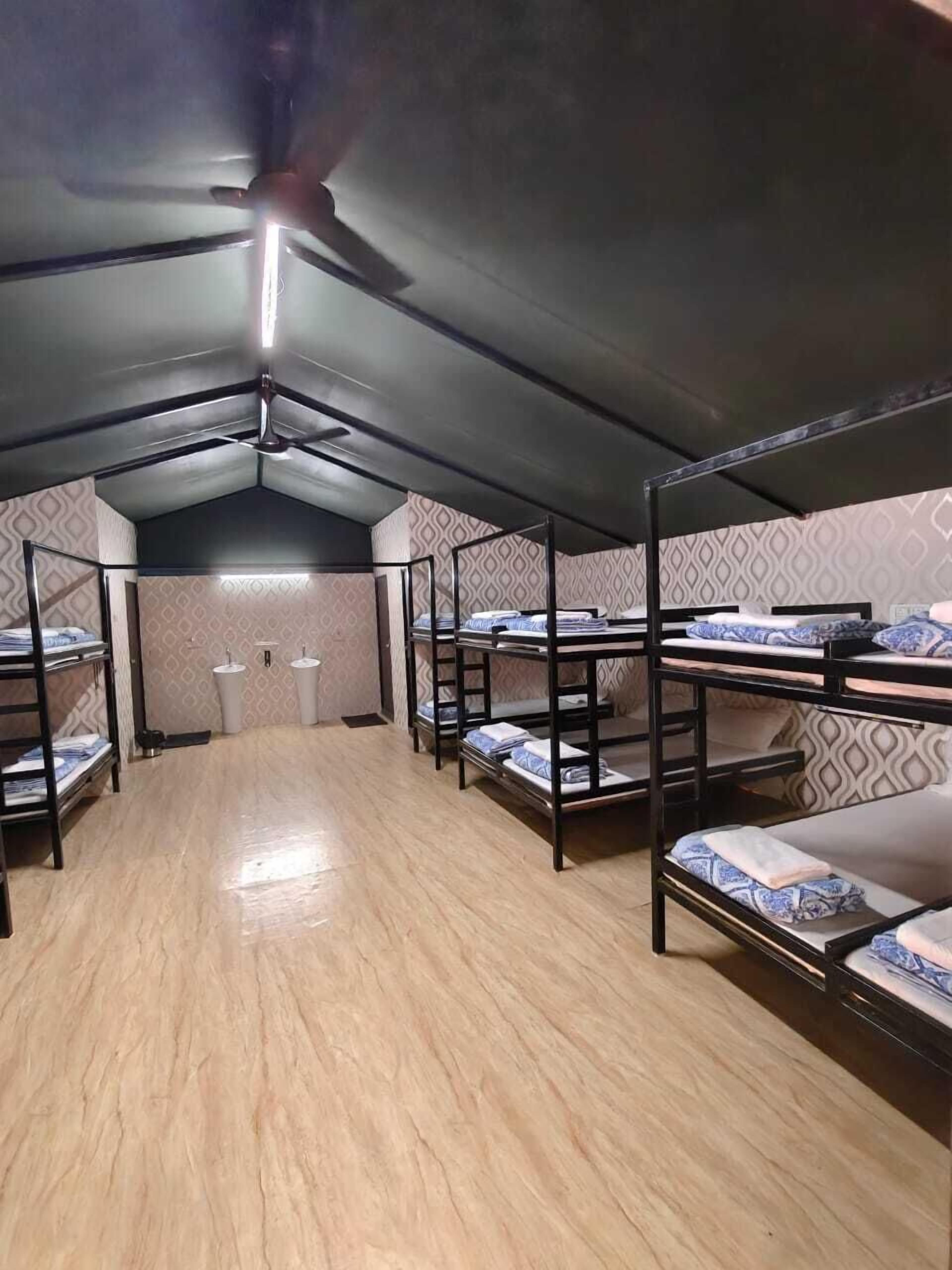 A dormitory room with bunk beds, a ceiling fan, and a patterned wall.