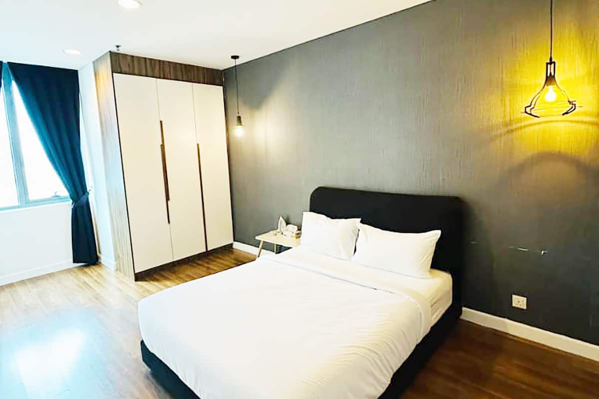 A modern bedroom with a large bed, a wardrobe, a nightstand, and a hanging light fixture.