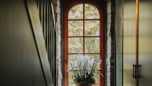 Un pasillo estrecho con suelo de madera, una ventana con marco de madera y una planta en maceta sobre el alféizar.