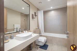 Een moderne badkamer met een groot wastafel, toilet en bad.