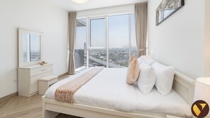 Ein modernes Schlafzimmer mit einem großen Bett, einem Nachttisch, einer Kommode und einem Fenster mit Blick auf die Stadt.