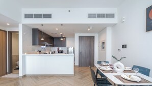 Eine moderne Küche mit einer zentralen Kochinsel, einem Essbereich mit Tisch für zwei Personen und einem Holzboden mit Fischgrätmuster.