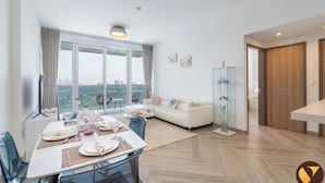 Ein modernes Wohnzimmer mit Essbereich, großen Fenstern und Blick auf die Stadt.