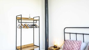 Une chambre à coucher avec un lit, un porte-manteau en bois et une table de chevet avec une lampe.