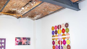 Une pièce avec un plafond en briques apparentes, des murs blancs et un motif circulaire coloré sur le mur.