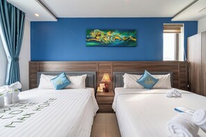 Una habitación de hotel con dos camas, un cuadro en la pared, una mesita de noche con una lámpara y vistas a la ciudad a través de la ventana.