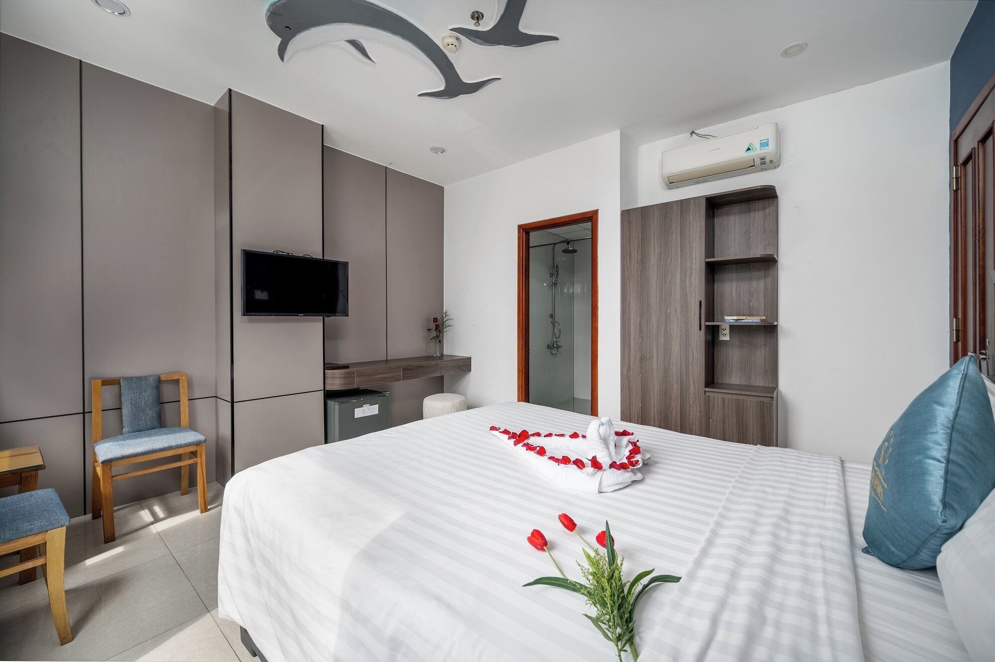 A modern hotel room with a bed, a TV, a shower, and a wardrobe.