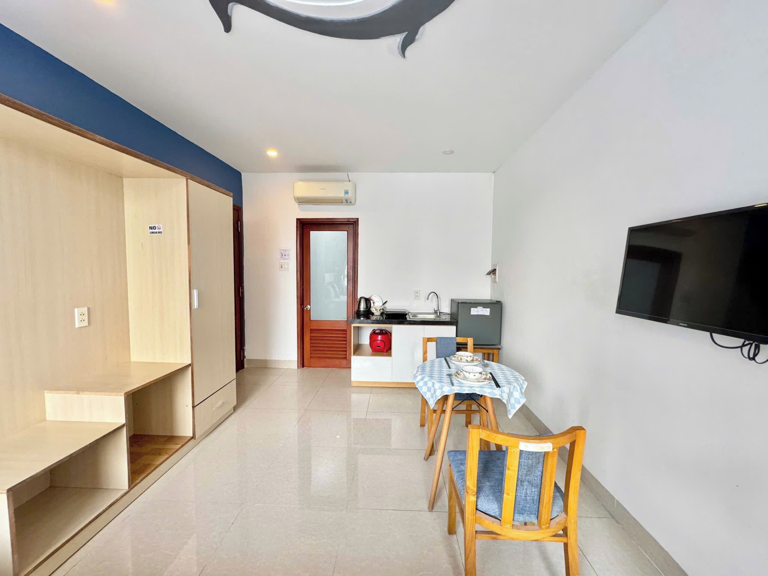 A compact living space with a kitchenette, a dining area with a table and chairs, and a mounted television.