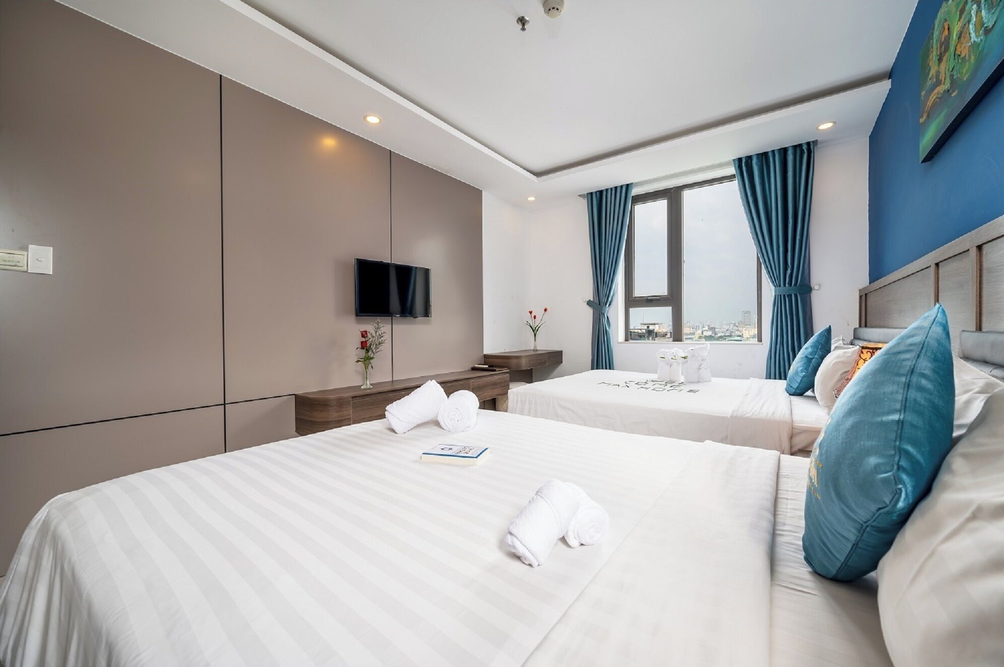 Une chambre d’hôtel avec deux lits, une télévision, un bureau et une fenêtre avec des rideaux.