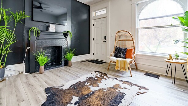 A room with a fireplace, a large window, a wicker chair, and a cowhide rug. - Short North & Downtown & OSU | Near High Street | Free Parking | 5,800+ Reviews (Columbus)