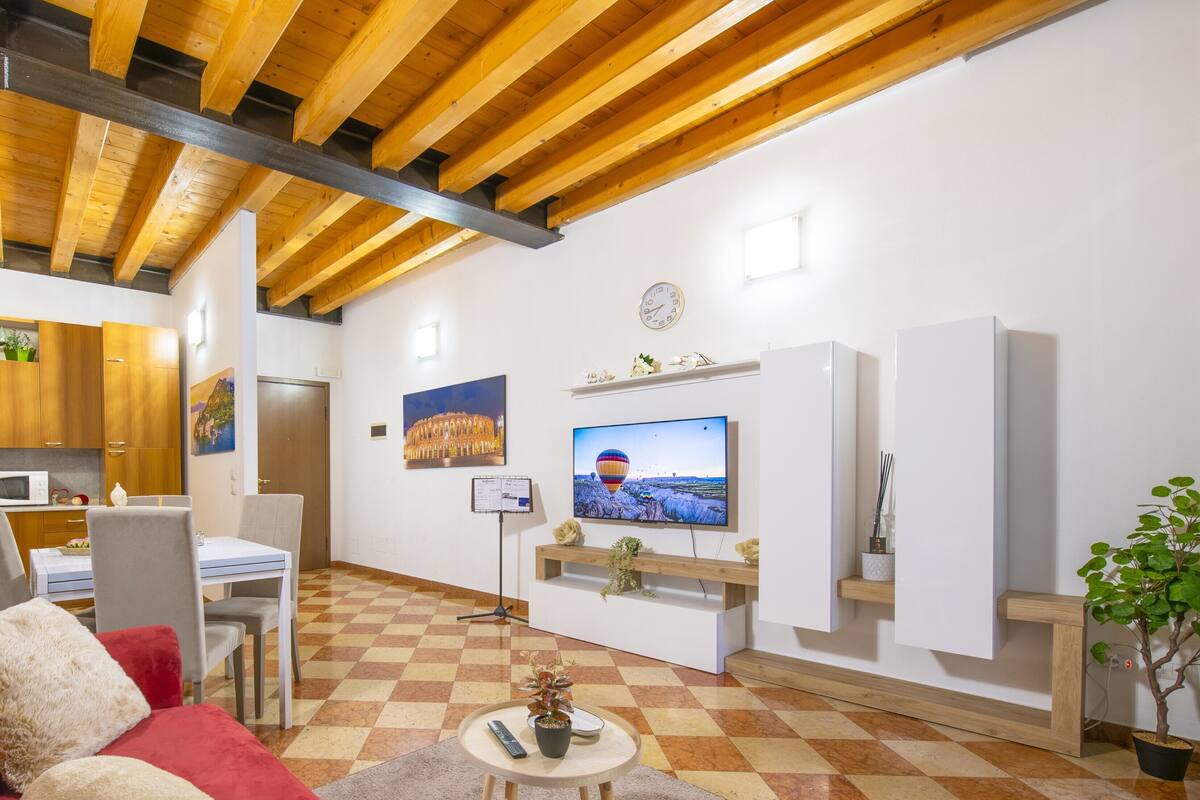 Un salon avec un sol à carreaux, un canapé rouge, un téléviseur et un plafond en bois.