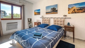 Ein Schlafzimmer mit einem großen Bett, einem Fenster und drei an der Wand befestigten Bildern.
