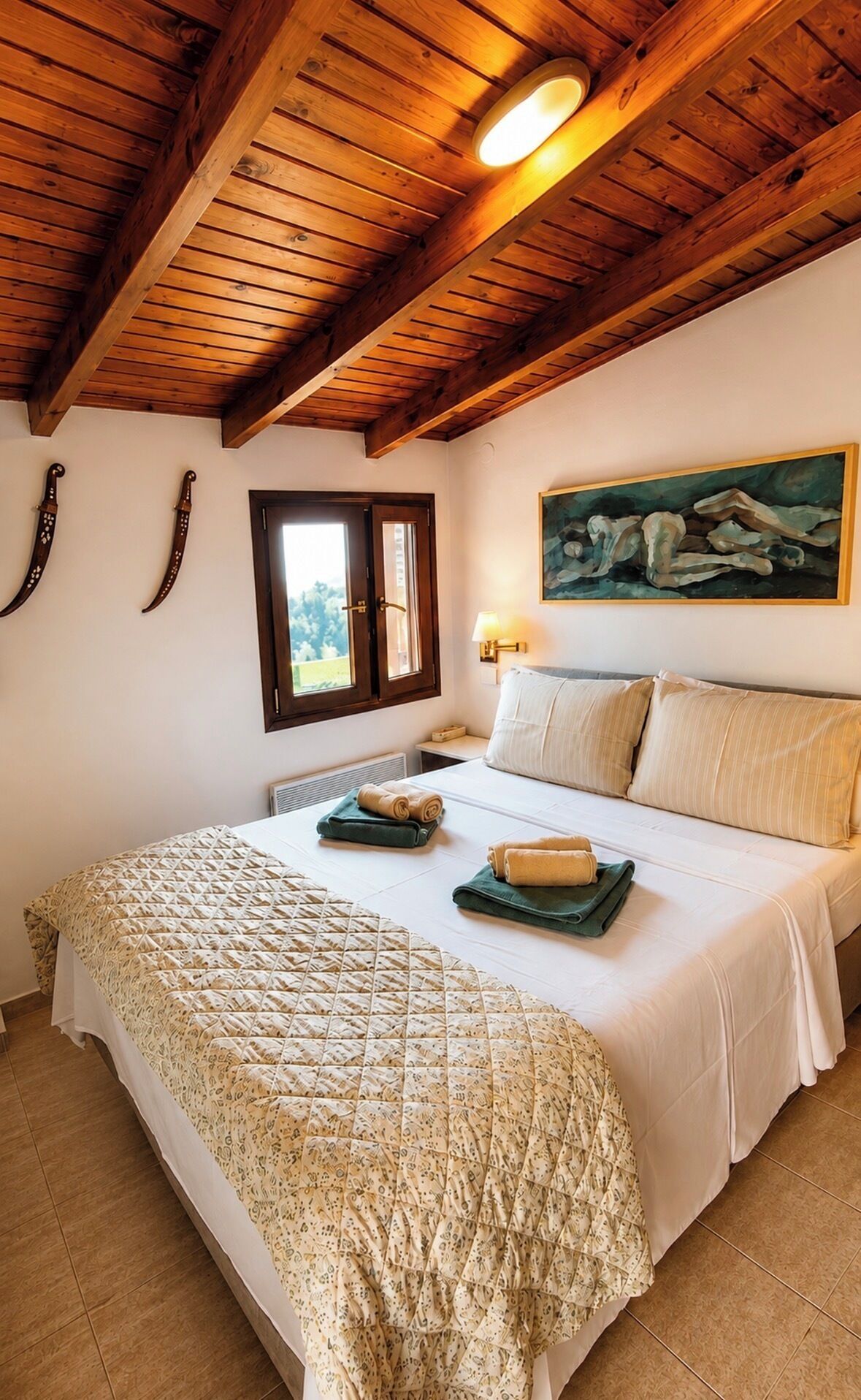 Un dormitorio con techo de madera, cama con colcha estampada, un cuadro en la pared y ventana con vista a vegetación.