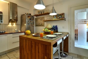 A kitchen with a wooden island, stainless steel appliances, and pendant lighting. - Portico Verde Private Villa With Pool Corfu (Corfu)