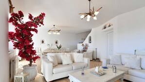 A spacious living room with white furniture, a large potted plant, and a white coffee table. - Dreamcatcher Sea View Mini Pool Paros (Paros)