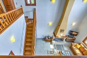 A spacious living area with a wooden staircase, a fireplace, a sofa, and a television. - Sea Front Stone Villa Near Monemvasia (Monemvasia)