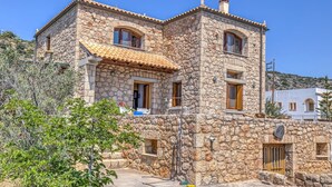 A stone building with a tiled roof, multiple windows, and a small balcony.