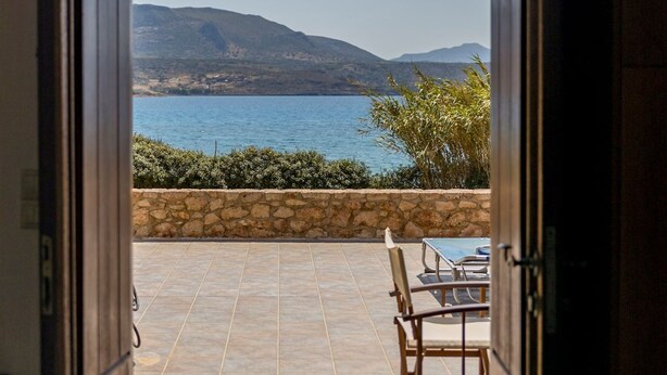 An open door leading to a patio with a view of the sea and mountains.