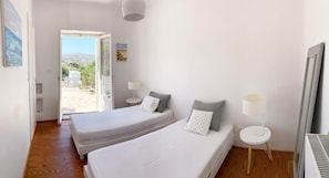 A bedroom with two beds, a window, a door, and a radiator. - Villa Joy in Ampelas Paros (Paros)