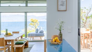 Een moderne kamer met een groot raam met uitzicht op een mooi panorama, een zithoek met houten meubels, en een tafeltje met een bloemenvaas.