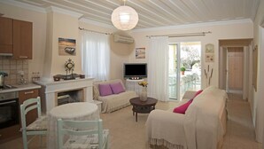 Un salon confortable avec un canapé, une table basse et un téléviseur. On y trouve également une cheminée et un coin repas avec des chaises et une table.