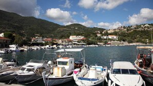 Un port de plaisance où sont amarrés des bateaux, entouré de collines et d’immeubles.