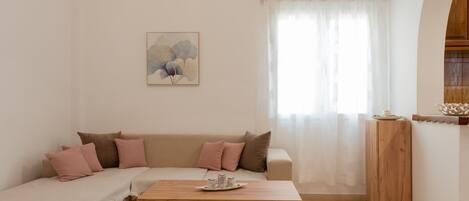 A cozy living room with a beige sofa, a wooden coffee table, and a painting on the wall.