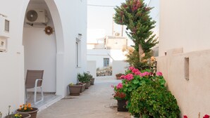 A narrow alleyway with white walls, potted plants, and a chair. - Naousa Central House Paros (Paros)