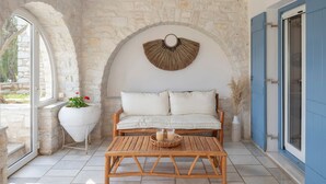 A cozy room with a stone wall, a wooden bench, and a woven wall hanging. - Sunrise Serenity Near Ambelas Beach (Paros)